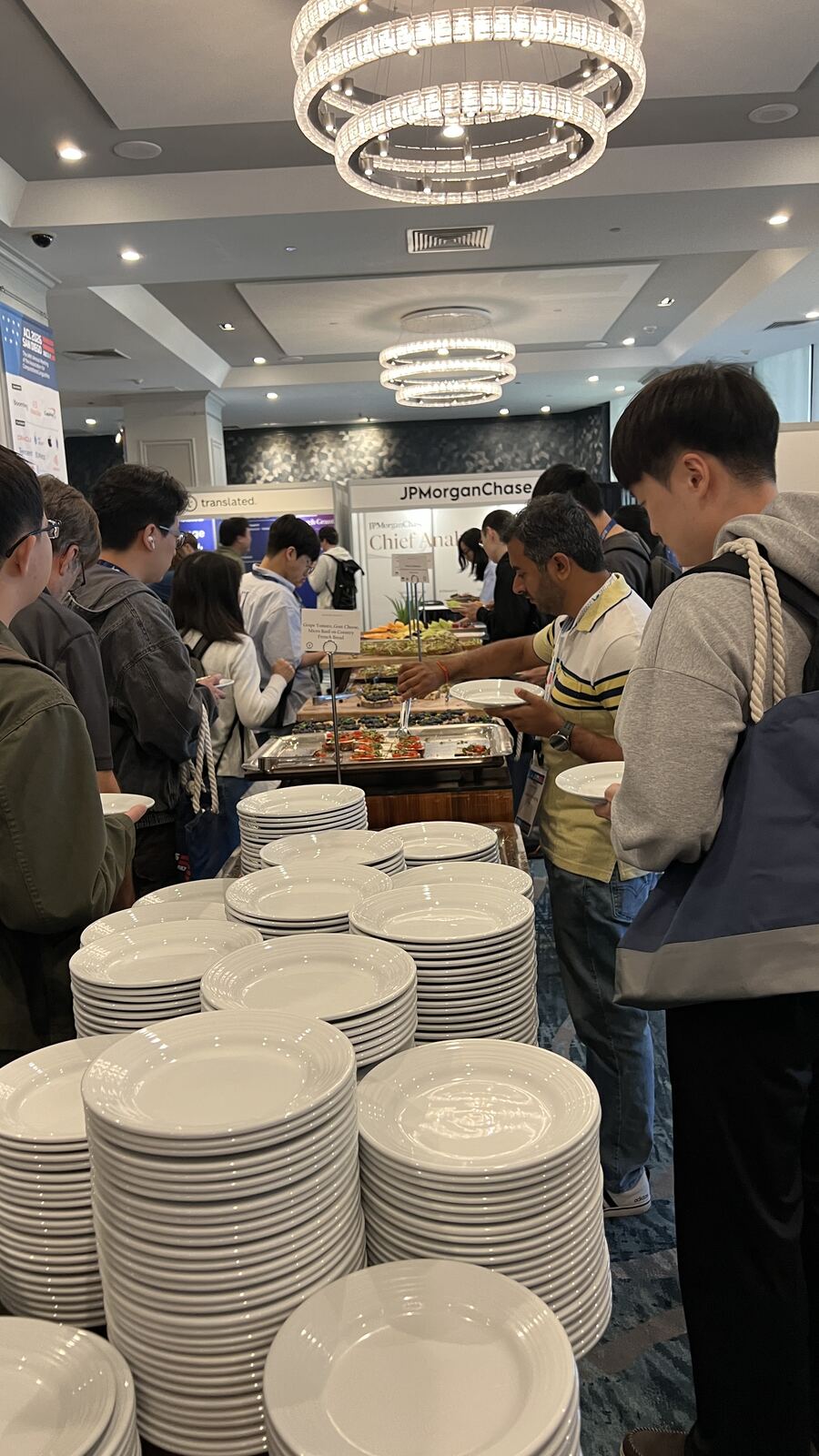 Attendees queueing at the ACL 2026 coffee-break buffet, with sponsor booths visible behind.