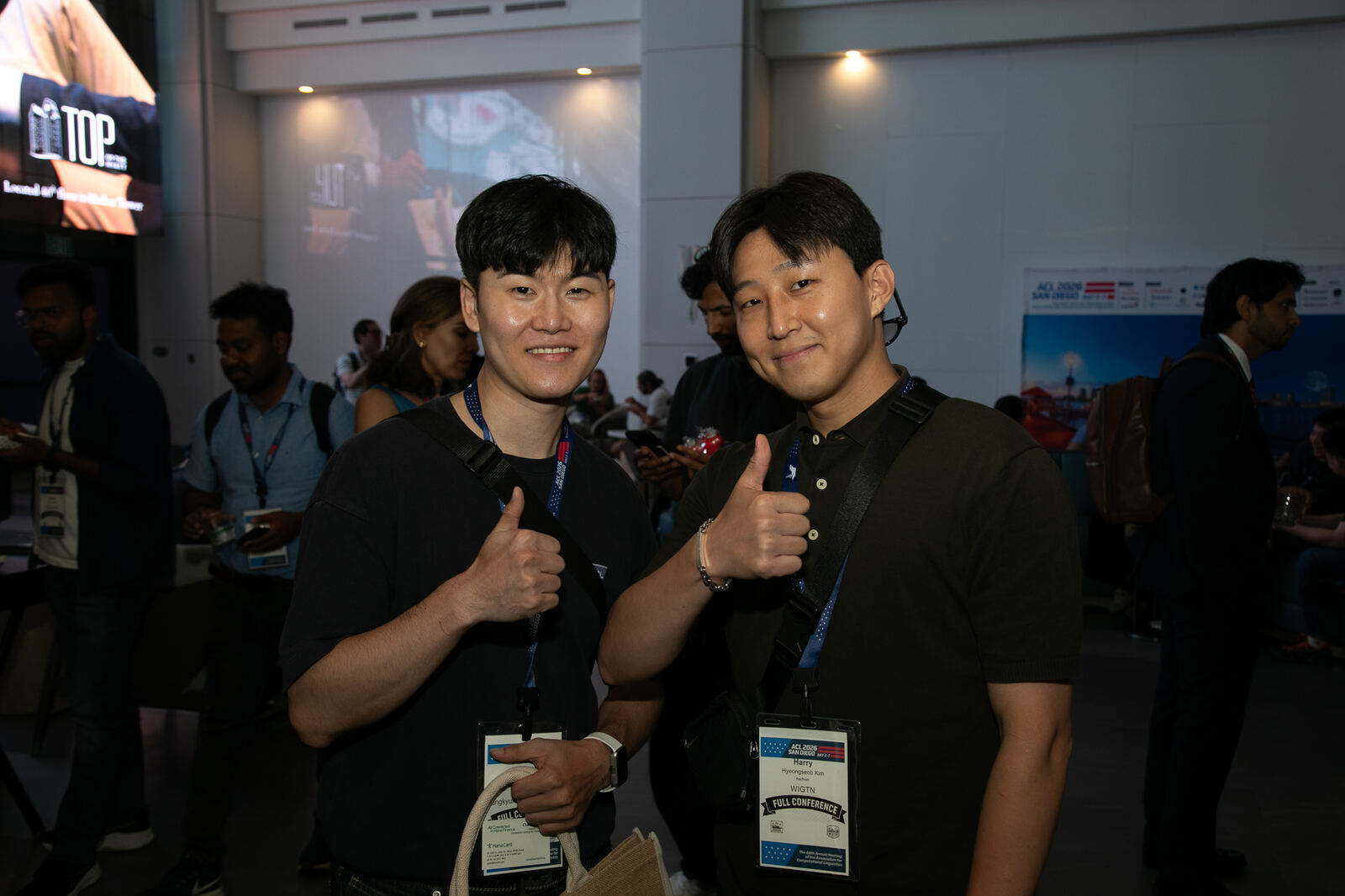 Two attendees photographed by the official ACL 2026 conference photographer in the venue foyer.