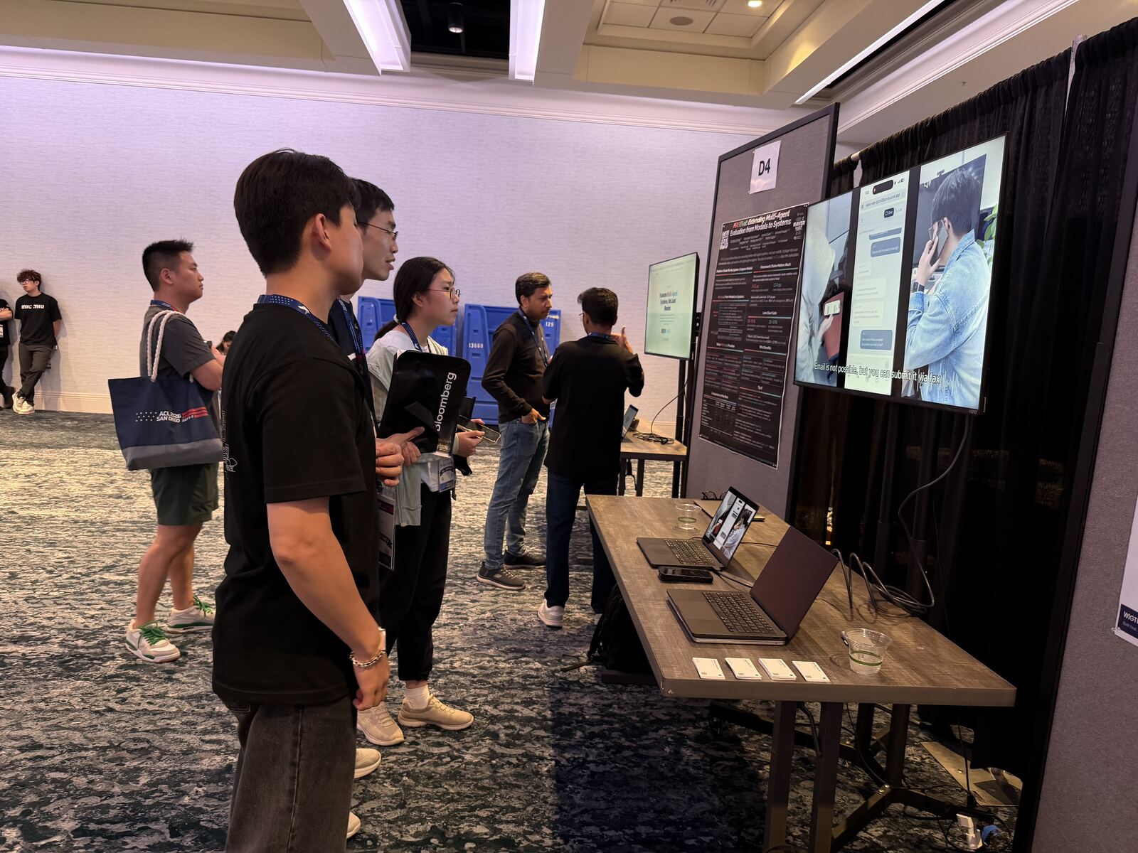 Visitors gathered in front of the WIGTN demo screens at ACL 2026, watching a live translated call.