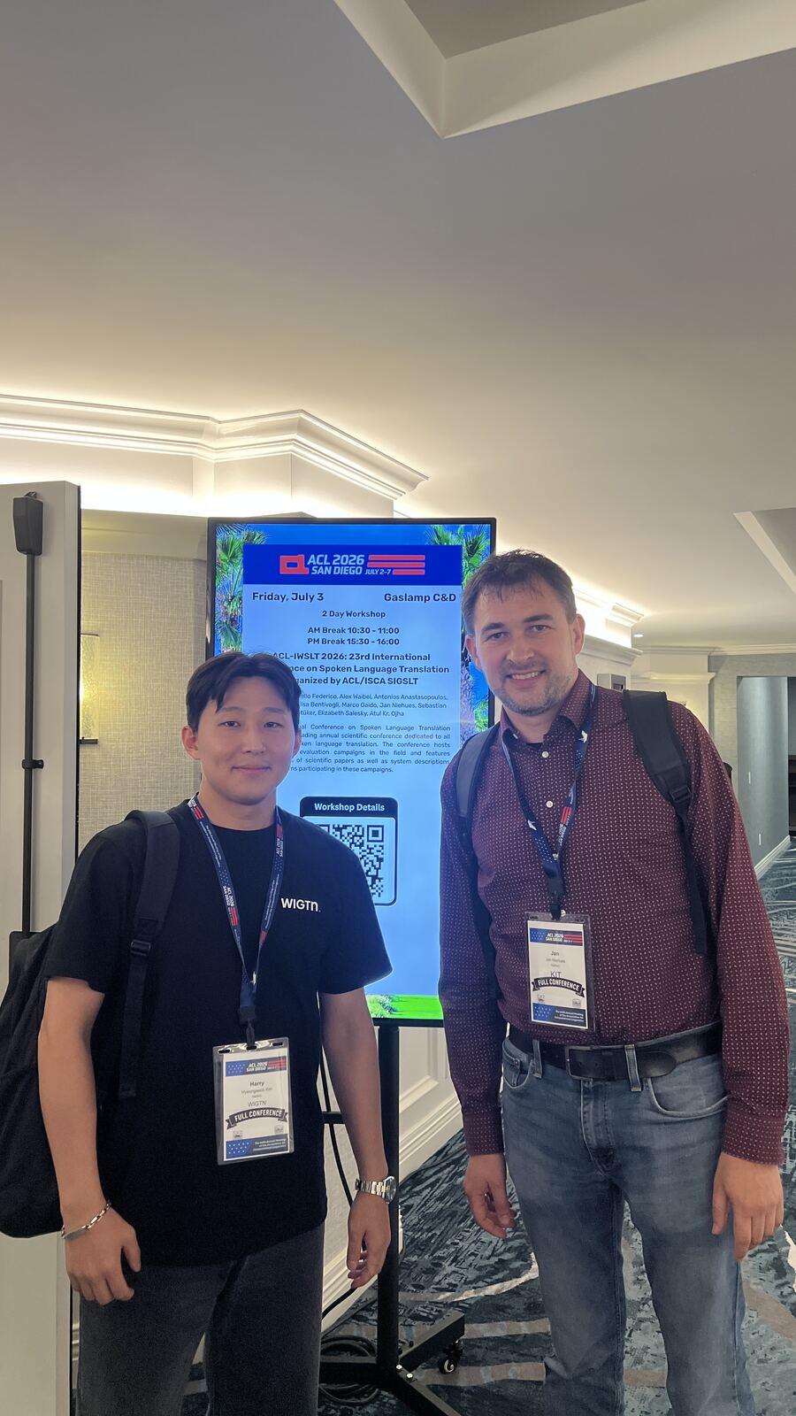 A WIGTN researcher with Jan Niehues of KIT in front of the ACL-IWSLT 2026 workshop signage.