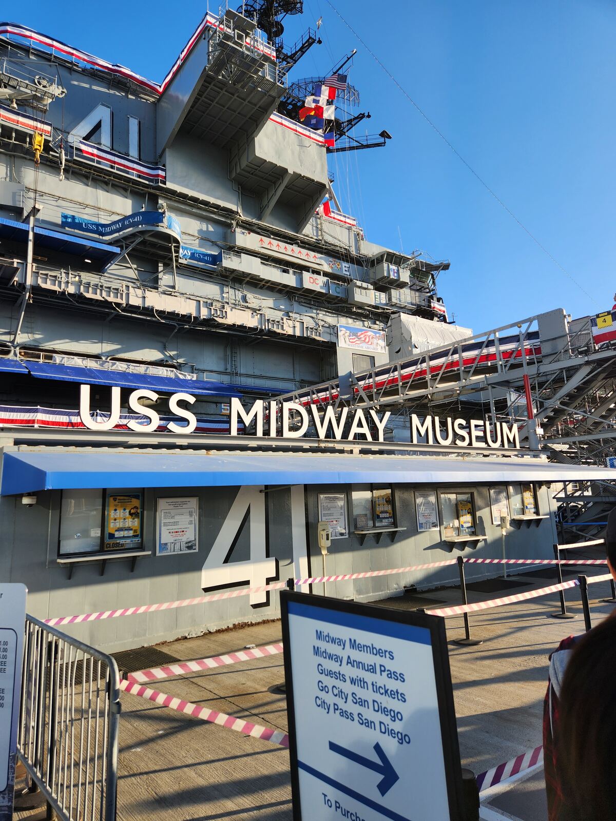 The entrance to the USS Midway Museum in San Diego, with the carrier's island and flags above the ticket booths.